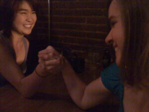 two women arm wrestling and smiling