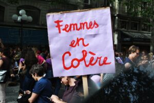 Picture of a white protest sign with "femmes en colère" written in red cursive text