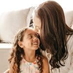 A mother kisses her little girl