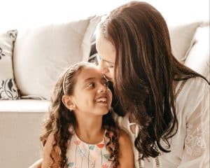 A mother kisses her little girl