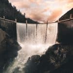 vertical image of a dam wiht four columns of water converging into a river over rocks