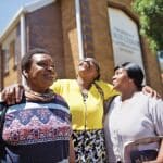 Three happy women outside a church building