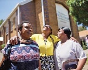 Three happy women outside a church building