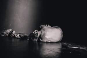 Black and white photo of white man curled into fetal position.