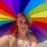 White woman holding rainbow umbrella