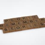 Scrabble tiles spelling out People Remember Stories on a white background