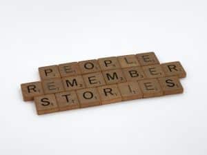 Scrabble tiles spelling out People Remember Stories on a white background