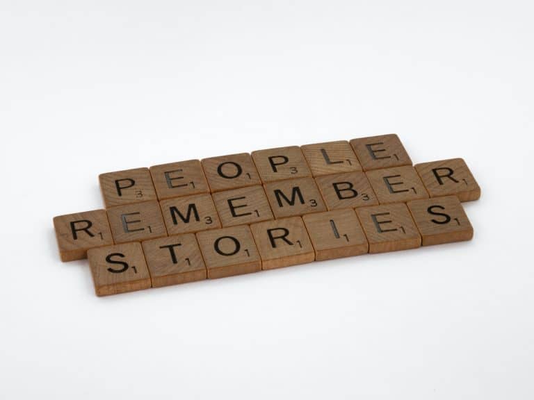 Scrabble tiles spelling out People Remember Stories on a white background