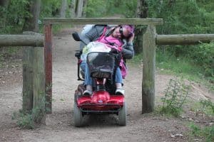 woman on scooter ducking under a wooden bar