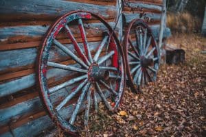 Two wagon wheels against log cabin.