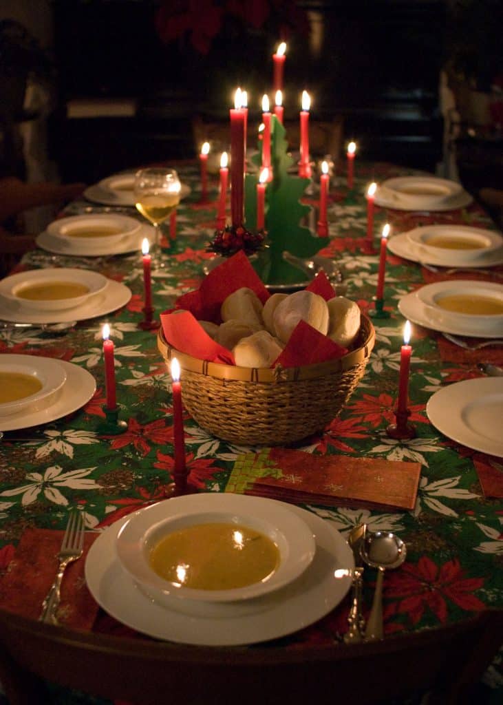 A holiday table, neatly laid, with many lit candles