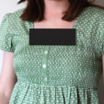 The chest of a woman wearing a maternity shirt, with the neckline censored.