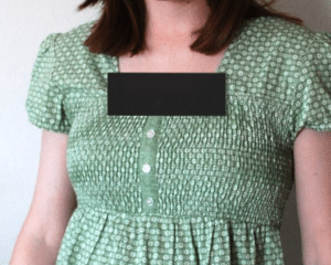 The chest of a woman wearing a maternity shirt, with the neckline censored.