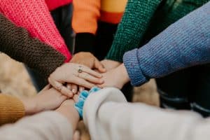 A group of people put their hands on top of each other to symbolize teamwork