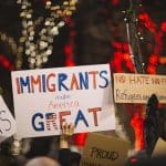 hands holding up posters welcoming immigrants and refugees