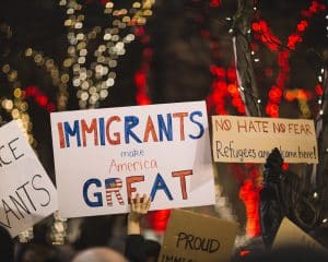 hands holding up posters welcoming immigrants and refugees