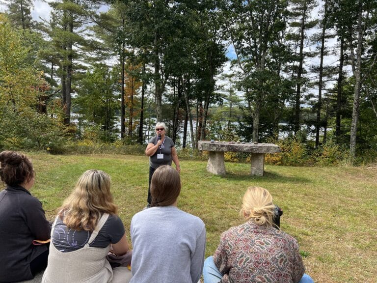 Nancy Dredge holding a microphone and speaking at the Exponent II retreat Quaker Meeting